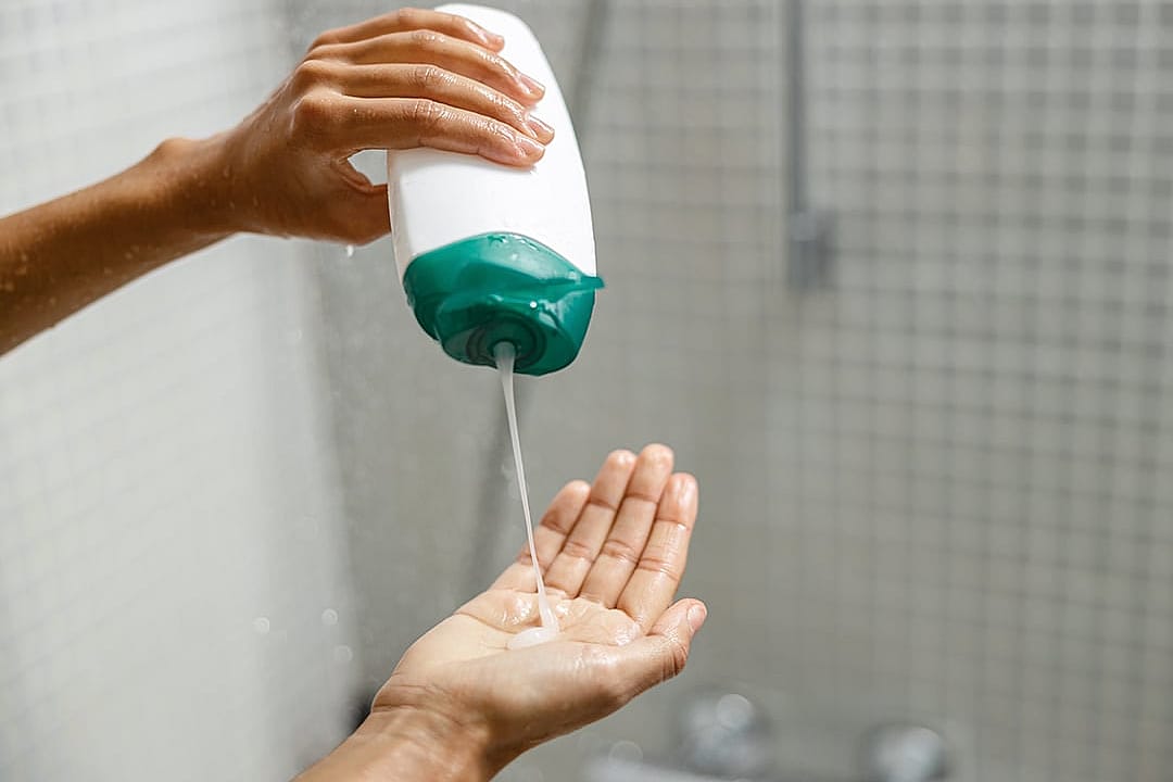 A person pouring a body wash gel on her hand during shower time.